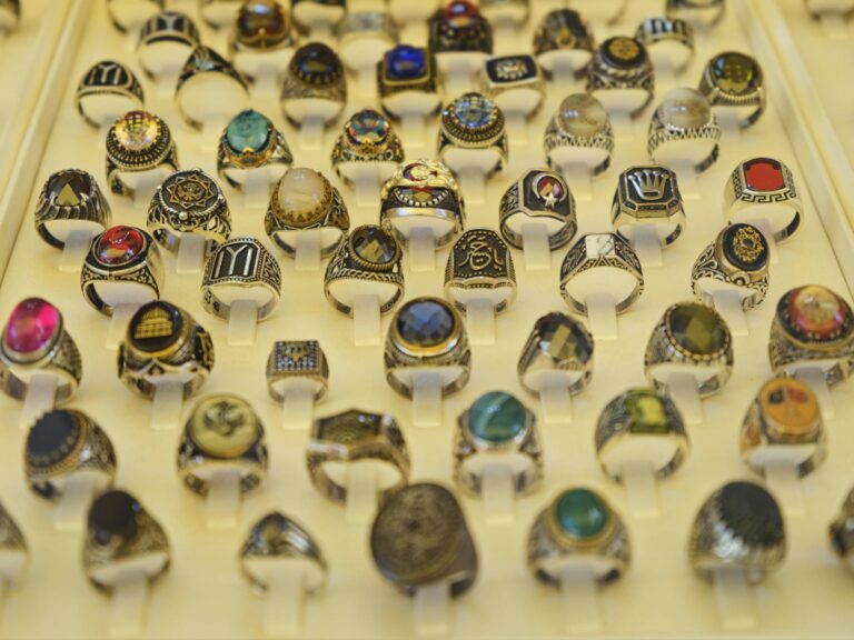 Close-up of assorted gemstone rings in a display case, showcasing intricate design and vibrant colors.